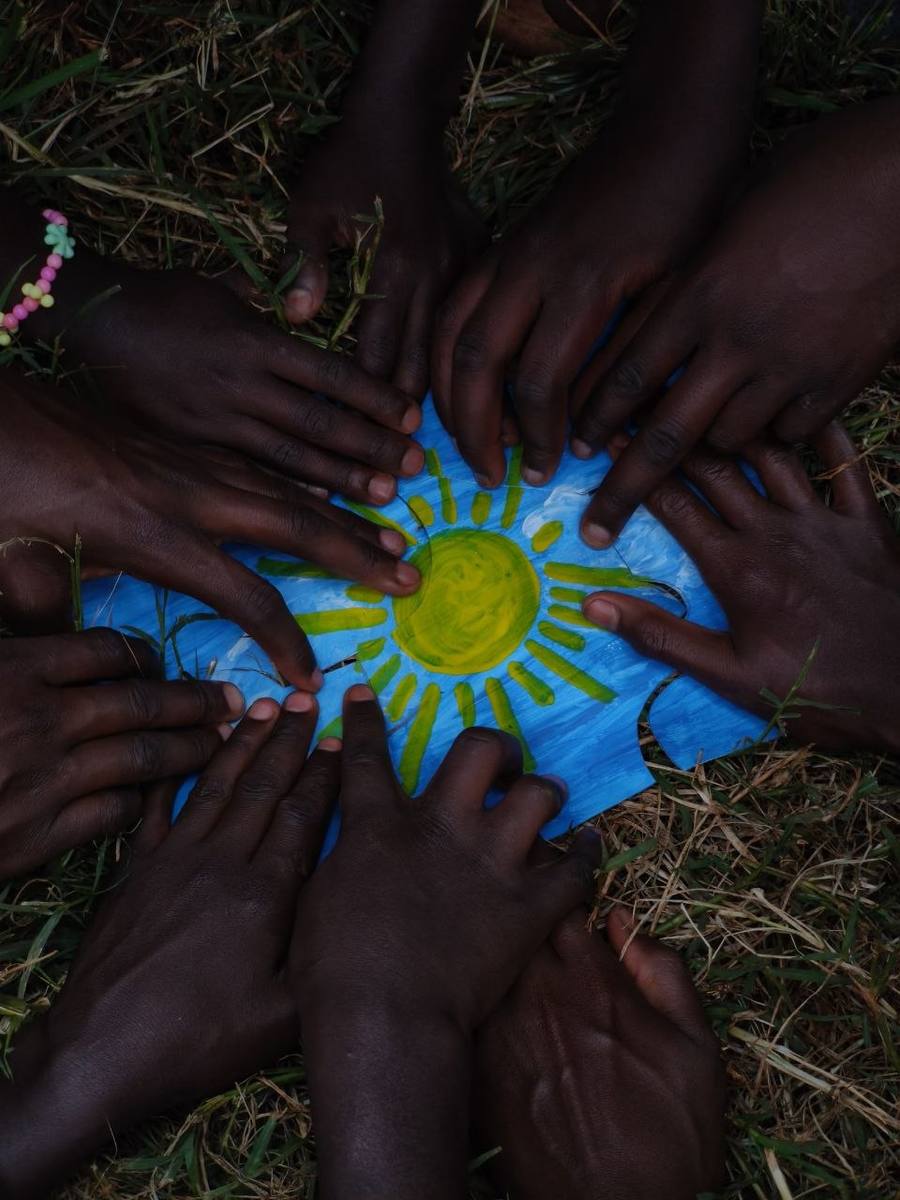 Mani di bambini che dipingono un sole