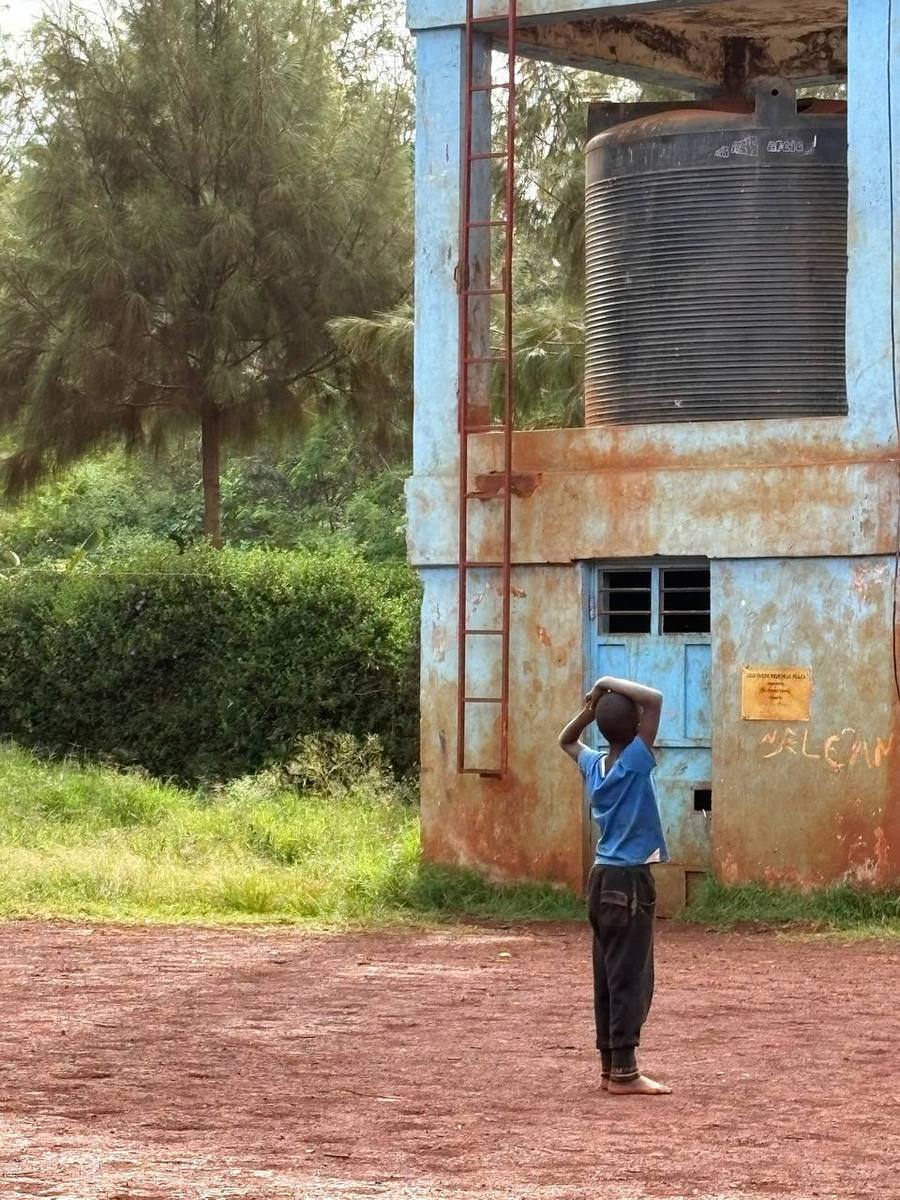 Un bambino davanti alla cisterna dell’acqua